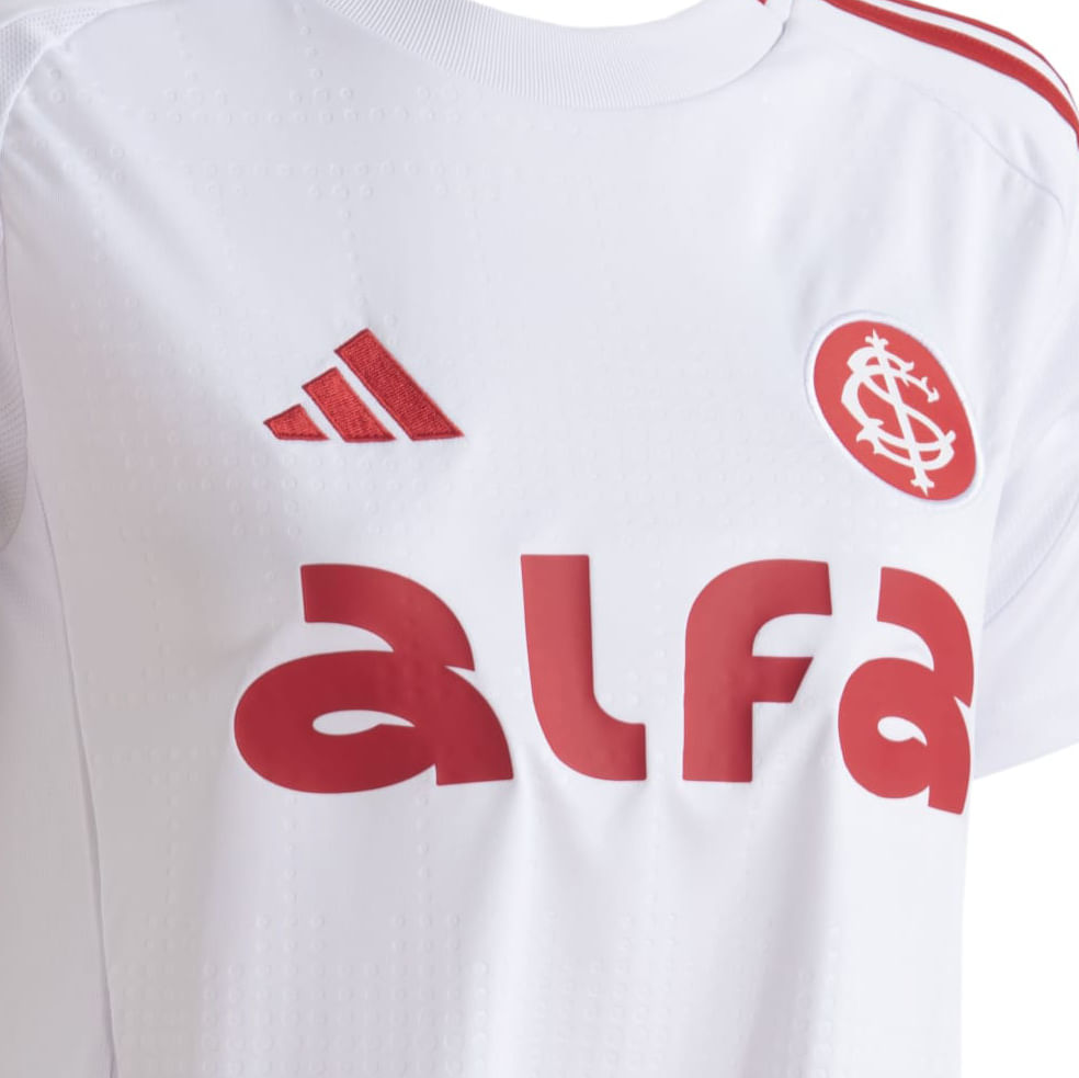 Detalhe da camisa infantil branca Adidas Internacional II com listras vermelhas e logos no peito e manga
